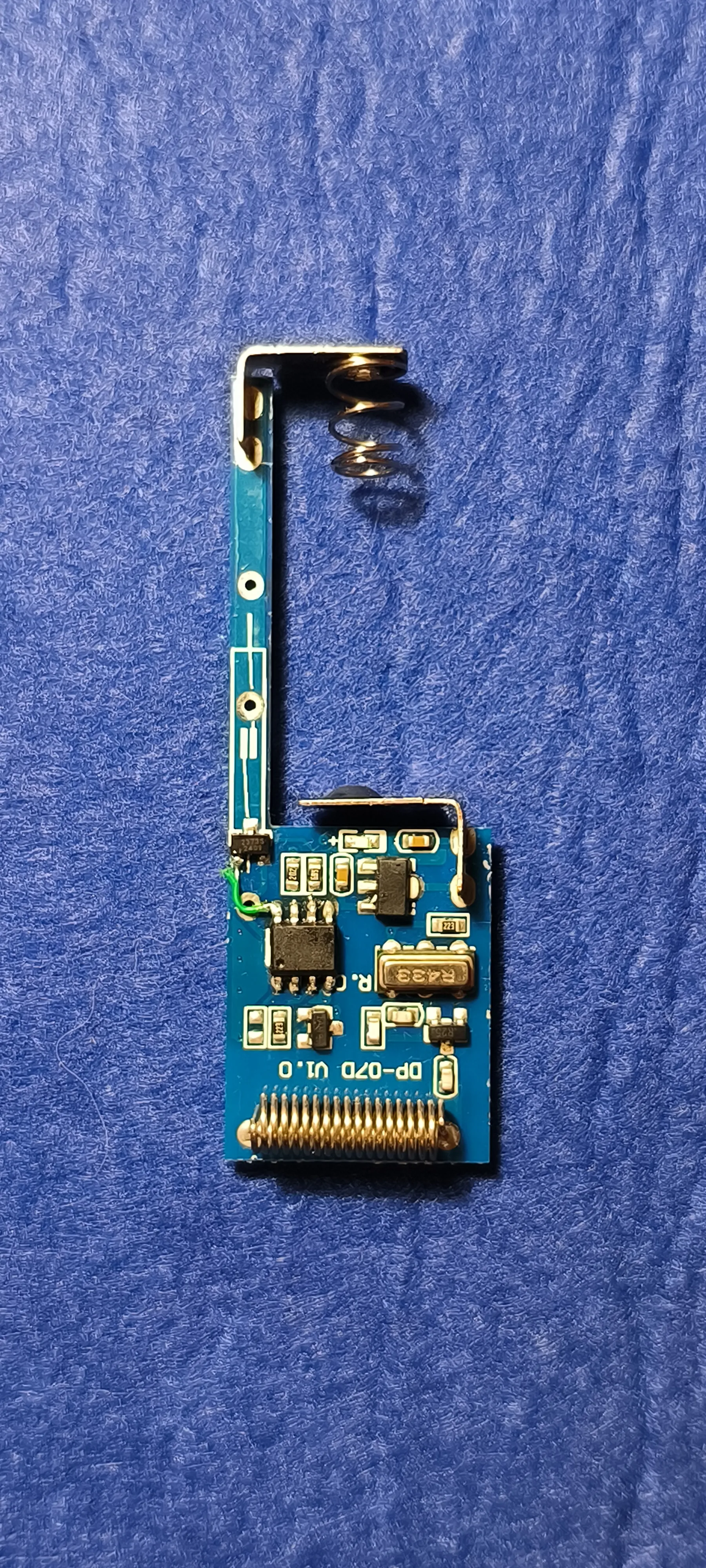 The board with the ATtiny13 soldered in place of the original chip, with a thin jumper wire routed to one of its pins